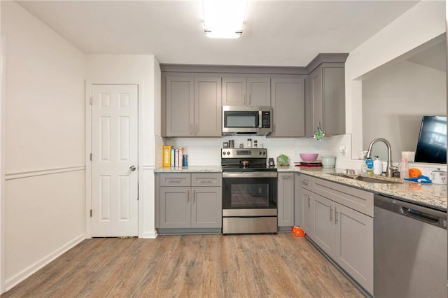 kitchen featuring appliances with stainless steel finishes, light hardwood / wood-style flooring, sink, and gray cabinetry