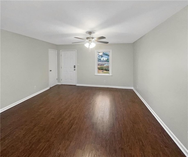 empty room with baseboards, dark wood finished floors, and a ceiling fan