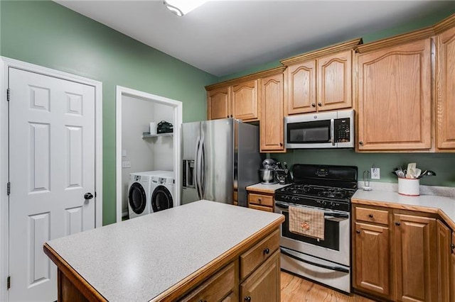 kitchen with a center island, light wood finished floors, stainless steel appliances, light countertops, and washer and dryer