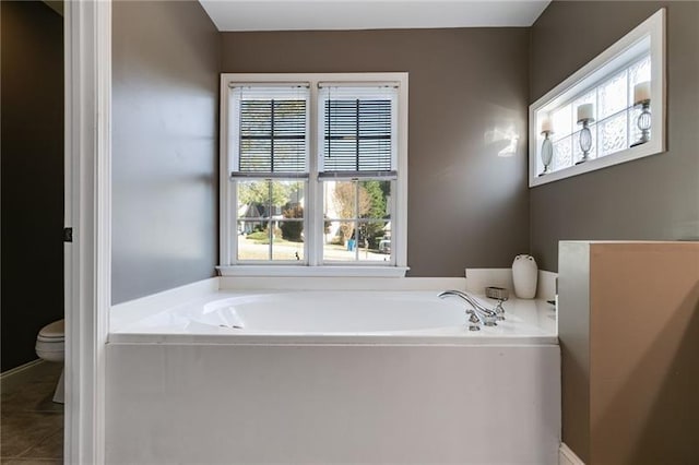 bathroom featuring tile patterned floors, toilet, and a bath