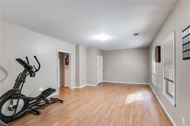 workout area featuring visible vents, light wood-style flooring, and baseboards