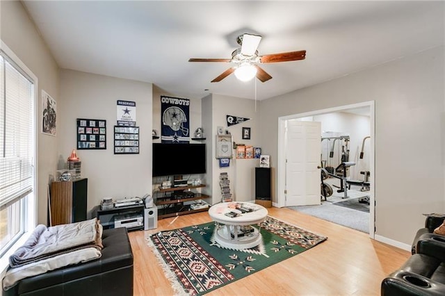 living room with light wood-style floors, baseboards, and a ceiling fan