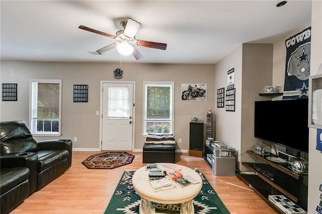 living area featuring light wood finished floors, baseboards, and a ceiling fan