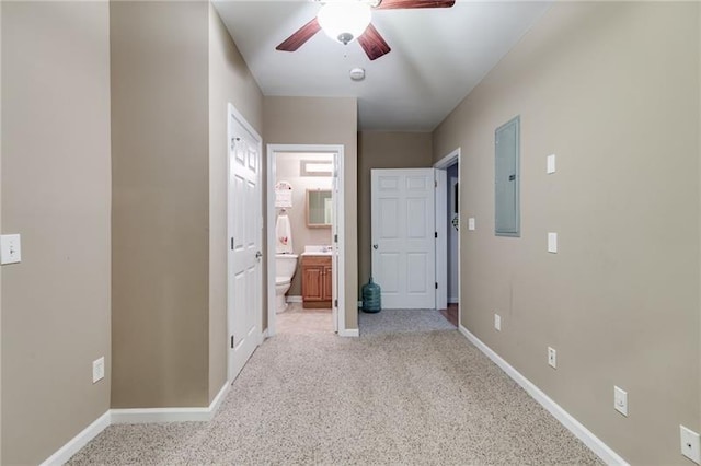 hallway with light carpet, electric panel, and baseboards