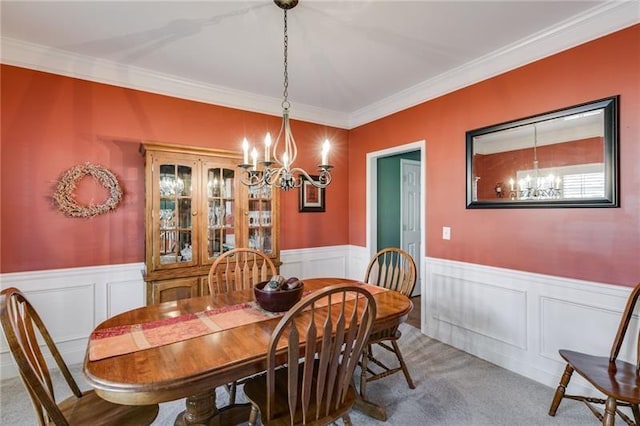 dining room with a wainscoted wall, carpet floors, crown molding, and a notable chandelier