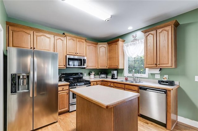 kitchen featuring appliances with stainless steel finishes, light countertops, a sink, and light wood finished floors