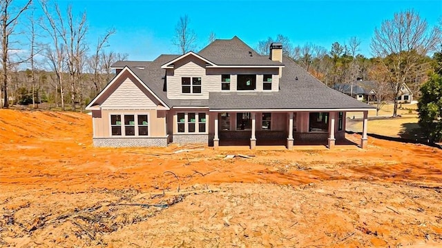 back of property with a porch, a chimney, and a shingled roof