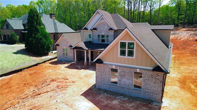 craftsman-style house featuring board and batten siding, a shingled roof, and brick siding