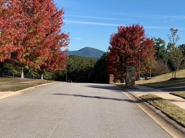 view of road with street lighting, curbs, sidewalks, and a mountain view
