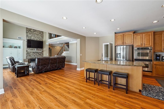kitchen with light wood-type flooring, stainless steel appliances, a breakfast bar, and recessed lighting