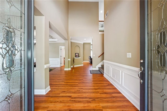 foyer entrance featuring a wainscoted wall, visible vents, wood finished floors, stairway, and a decorative wall