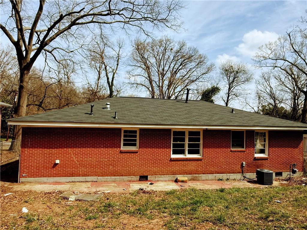 rear view of house featuring cooling unit and brick siding