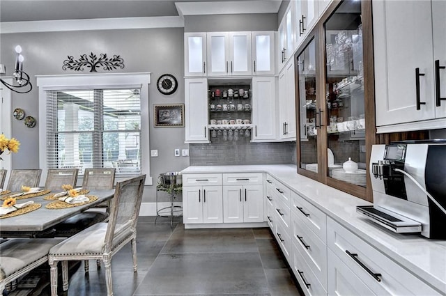 kitchen featuring dark tile floors, backsplash, and white cabinetry