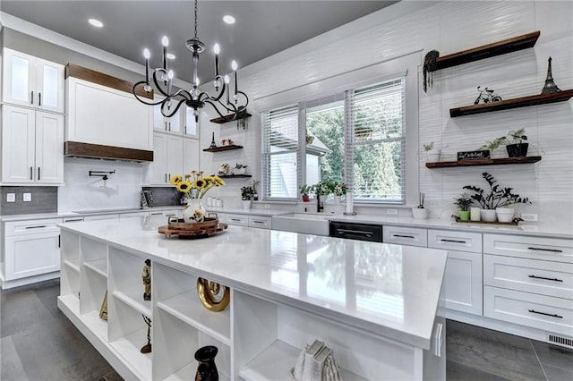 kitchen with decorative light fixtures, a kitchen island, backsplash, white cabinetry, and sink