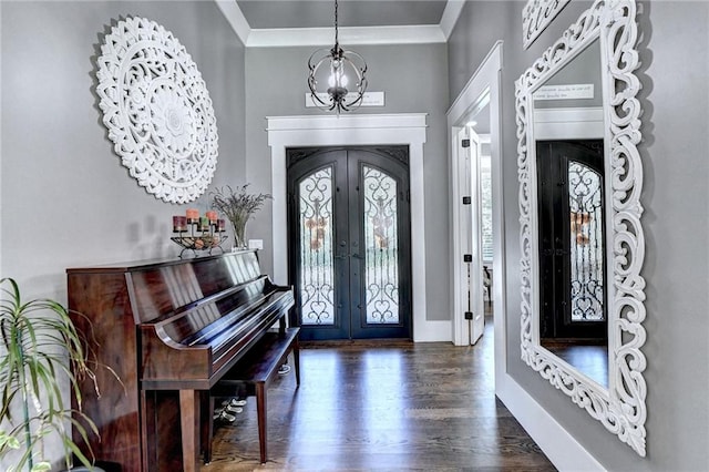 entrance foyer with a notable chandelier, french doors, dark hardwood / wood-style floors, and ornamental molding