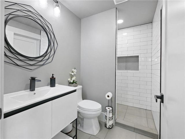 bathroom with tiled shower, vanity, toilet, and tile floors