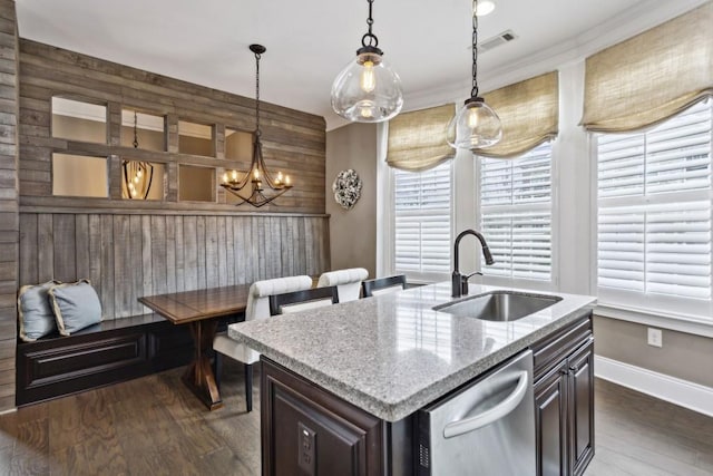 kitchen featuring stainless steel dishwasher, hanging light fixtures, sink, and a center island with sink