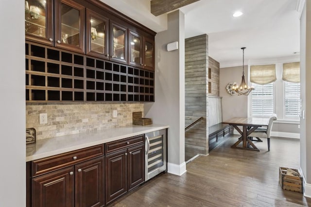 bar with dark brown cabinets, pendant lighting, wine cooler, and decorative backsplash