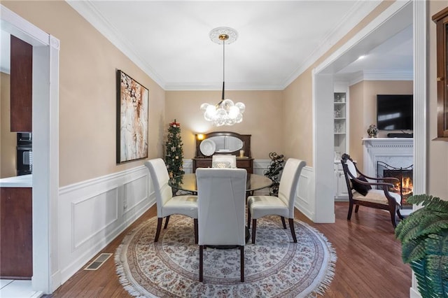 dining space with dark hardwood / wood-style flooring, crown molding, a premium fireplace, and a chandelier