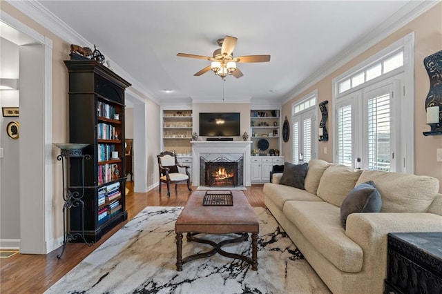 living room featuring crown molding, french doors, built in shelves, and hardwood / wood-style flooring