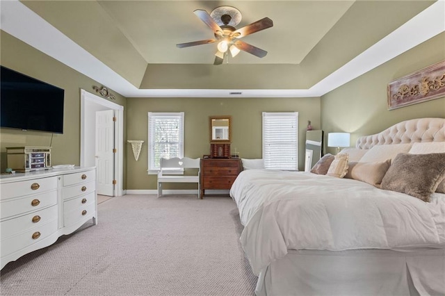 carpeted bedroom featuring ceiling fan and a raised ceiling