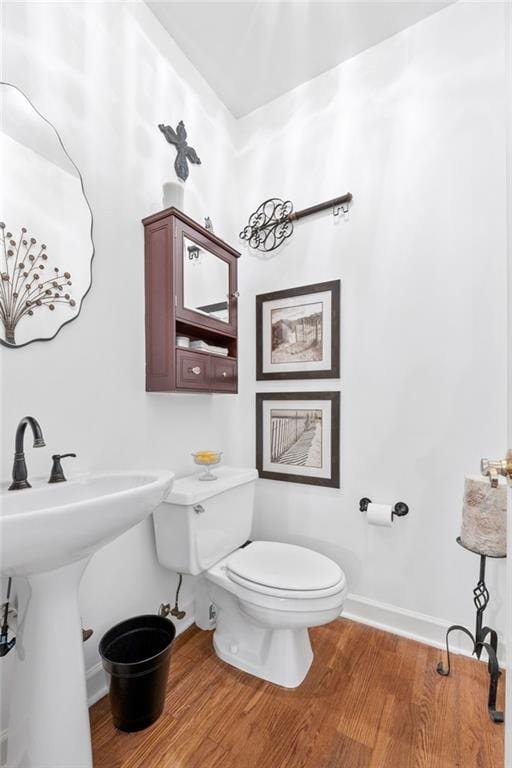 bathroom with wood-type flooring, toilet, and sink