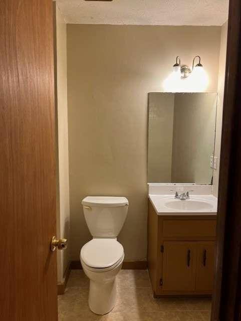 bathroom with tile patterned flooring, vanity, a textured ceiling, and toilet