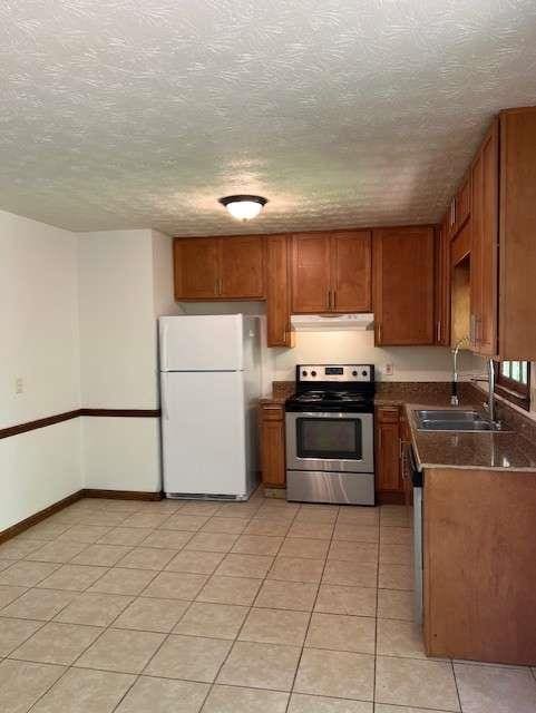 kitchen featuring stainless steel appliances, sink, a textured ceiling, and light tile patterned floors