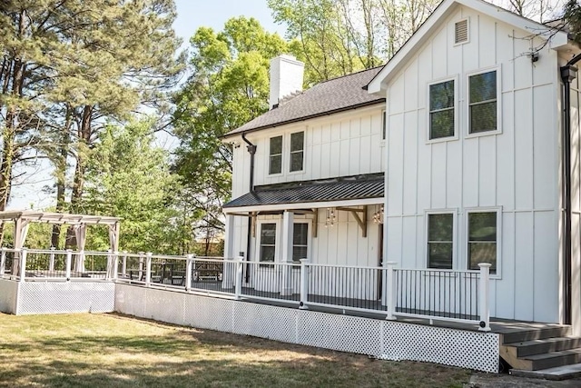 rear view of property featuring a yard and a pergola