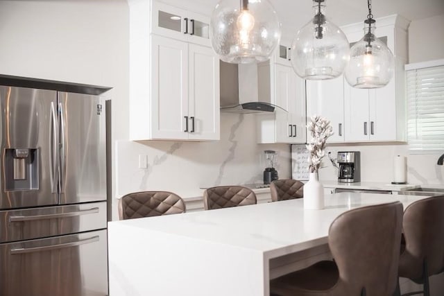 kitchen with pendant lighting, a kitchen bar, white cabinetry, and stainless steel refrigerator with ice dispenser