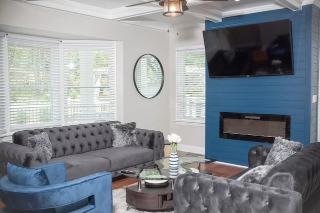 living room featuring hardwood / wood-style flooring, ornamental molding, a healthy amount of sunlight, and a large fireplace