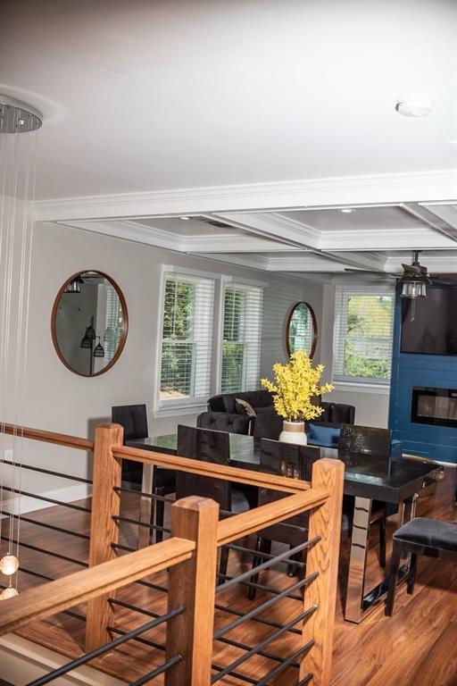 dining area featuring hardwood / wood-style flooring, crown molding, and a large fireplace