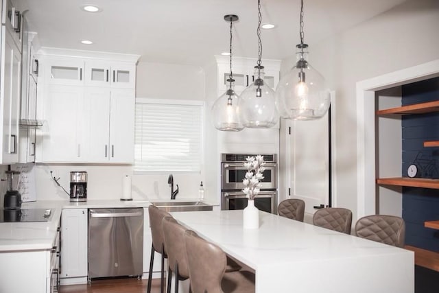 kitchen with hanging light fixtures, stainless steel appliances, sink, and white cabinets