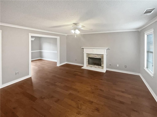 unfurnished living room with a textured ceiling, dark hardwood / wood-style flooring, a stone fireplace, and ceiling fan