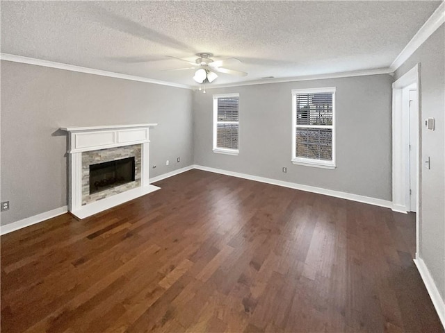 unfurnished living room featuring a stone fireplace, dark hardwood / wood-style floors, ceiling fan, ornamental molding, and a textured ceiling