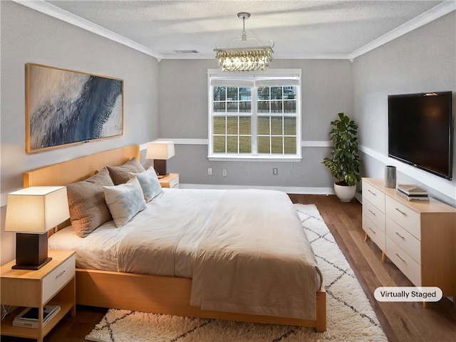 bedroom with a notable chandelier, dark hardwood / wood-style floors, ornamental molding, and a textured ceiling