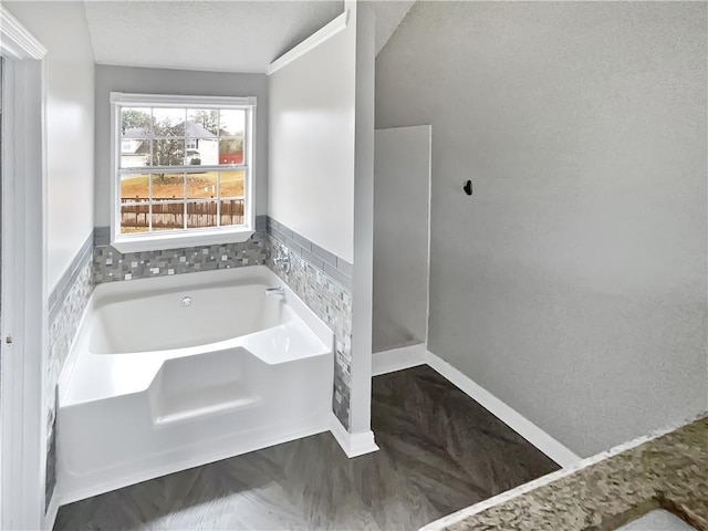 bathroom featuring a textured ceiling and a tub to relax in