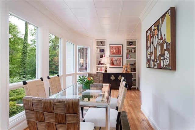 dining space with light hardwood / wood-style flooring, built in features, and a healthy amount of sunlight