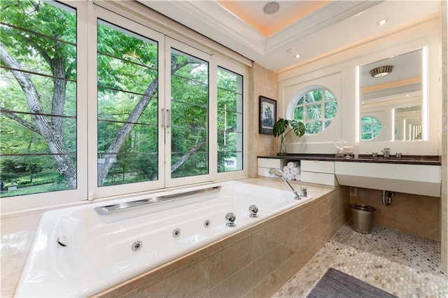 bathroom featuring tiled tub, sink, and ornamental molding