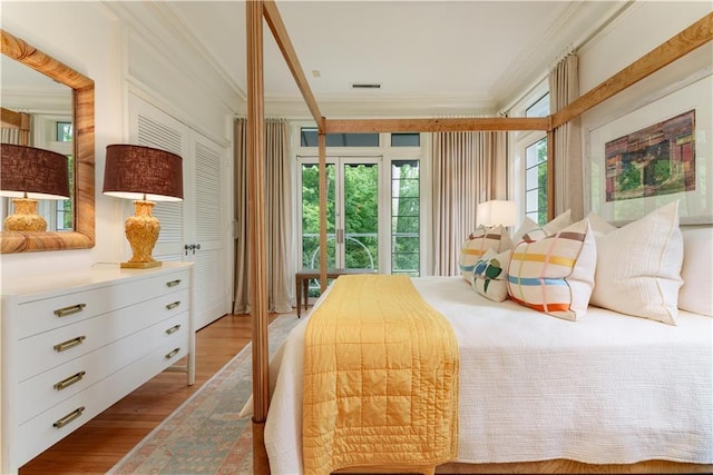 bedroom with light wood-type flooring, multiple windows, and crown molding