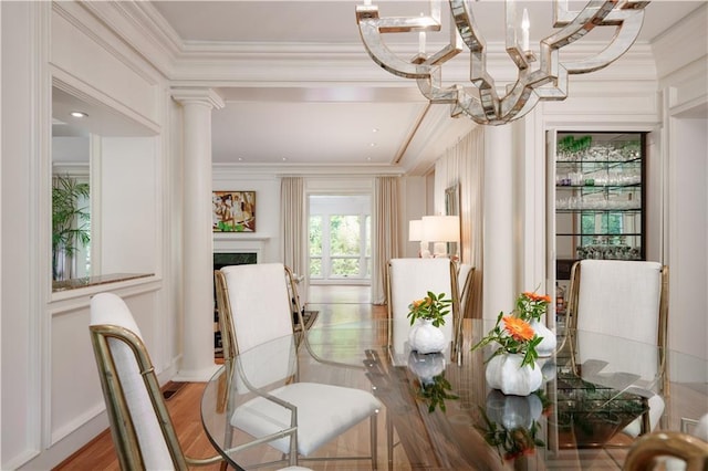 living area with a fireplace, light wood-type flooring, ornamental molding, and a chandelier