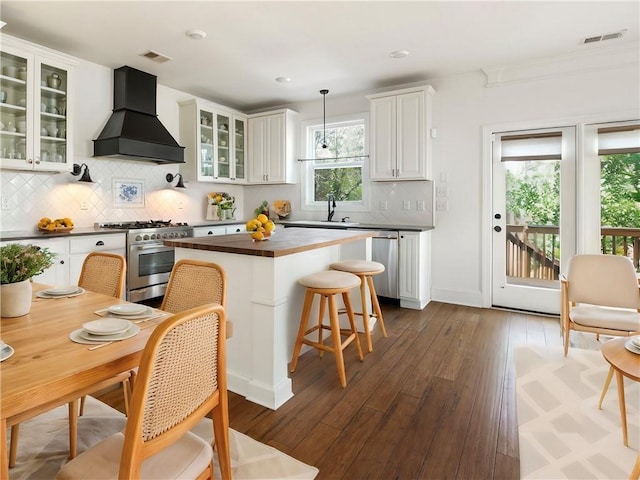 kitchen featuring premium range hood, white cabinetry, appliances with stainless steel finishes, dark hardwood / wood-style flooring, and pendant lighting