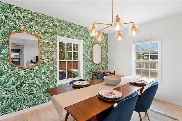 dining space with baseboards, wood finished floors, an accent wall, and wallpapered walls