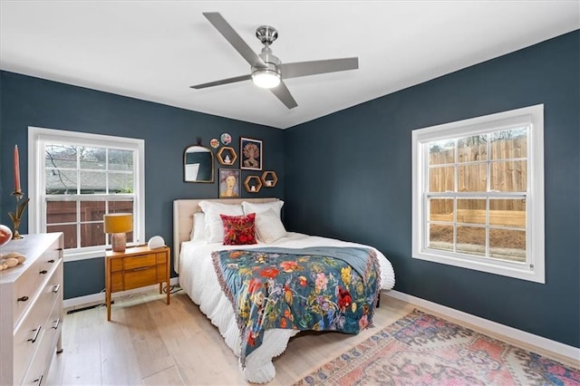 bedroom with a ceiling fan, baseboards, and light wood-type flooring