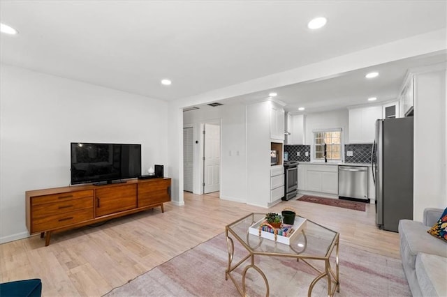 living room with recessed lighting, visible vents, baseboards, and light wood-style flooring