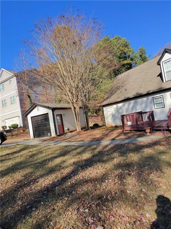 view of property exterior featuring a yard, a wooden deck, an outbuilding, and a garage