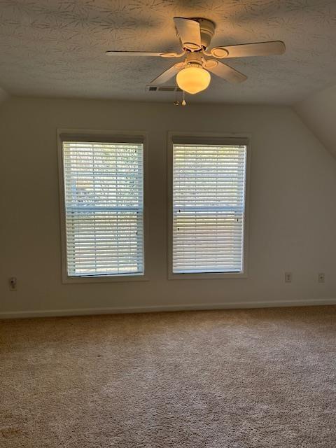 unfurnished bedroom featuring ceiling fan, a textured ceiling, lofted ceiling, light carpet, and a closet