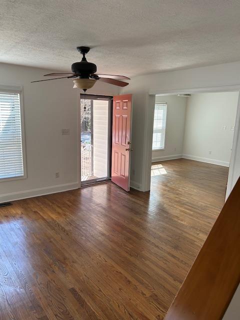 unfurnished living room featuring dark hardwood / wood-style floors, ceiling fan, and a tiled fireplace