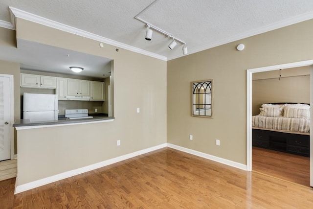 kitchen with under cabinet range hood, white appliances, a textured ceiling, and light wood-style floors