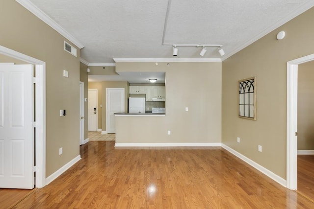 unfurnished living room with visible vents, baseboards, light wood-style floors, and ornamental molding